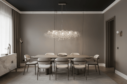 Contemporary glass branch chandelier suspended over a dining table in a modern dining room with warm ambient evening lighting and minimalist decor.